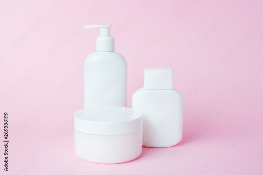 White jars of cosmetics on a pink background. Bath accessories. Face and body care concept