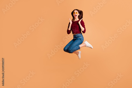 Full length side profile body size photo beautiful she her lady jumping high ideal appearance hands arms fists raised wear specs casual red burgundy knitted pullover isolated pastel beige background