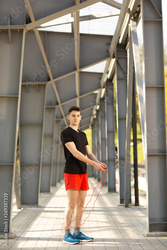 Young man skipping with jump rope outdoors. Exercising and lifestyle concept