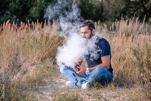 Modern man enjoying an e-cigarette. Man really likes process of smoking.