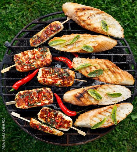 Grilled halloumi cheese with the addition of mint and chilli pepper and grilled herb toasts from a baguette while grilling outdoors, top view. Delicious, vegetarian, grilled appetizers