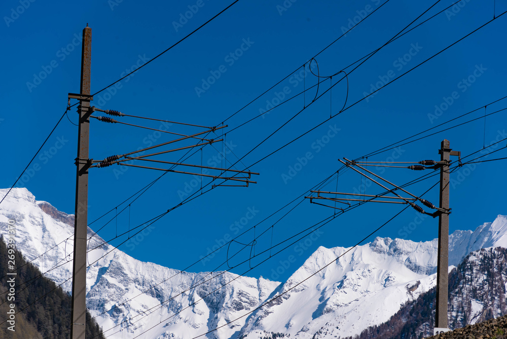 Eisenbahn Oberleitung, blauer HImmel, schneebedeckte Berge Eisenbahn Oberleitung, blauer HImmel, schneebedeckte Berge