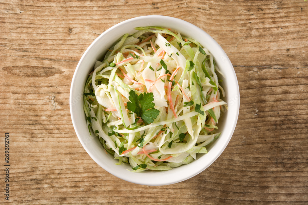 Coleslaw salad in white bowl on wooden table. Top view Coleslaw salad in white bowl on wooden table. Top view