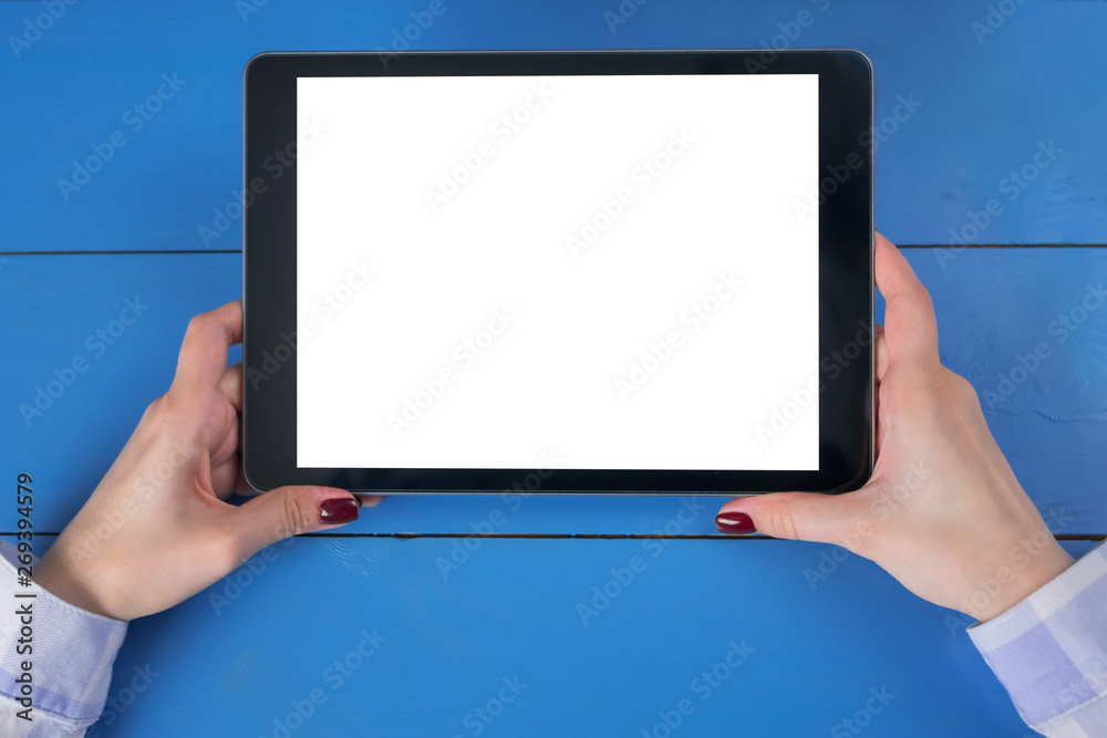 Woman sitting and looking at digital tablet computer device with white blank screen on blue wooden table - top view. Mock up, entertainment, copyspace, template, leisure time and technology concept Woman sitting and looking at digital tablet computer device with white blank screen on blue wooden table - top view. Mock up, entertainment, copyspace, template, leisure time and technology concept