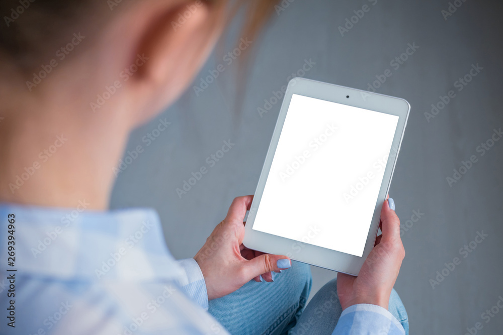 Woman sitting and looking at digital tablet computer device with white blank screen. Mock up, entertainment, copyspace, template, leisure time and technology concept 