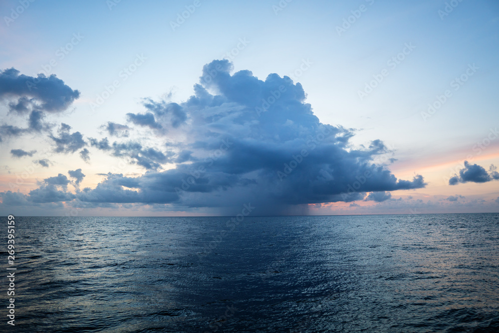 sunset, sea, the sun is covered with clouds. Open ocean view from boat with storm coming