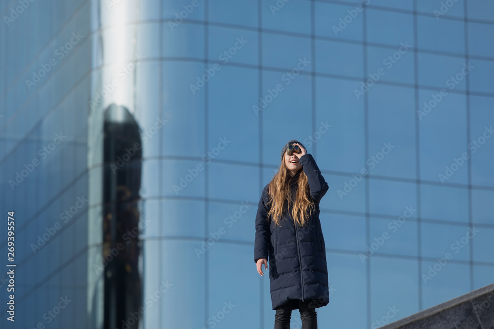 young woman looking at the binocular in front of the business building young woman looking at the binocular in front of the business building