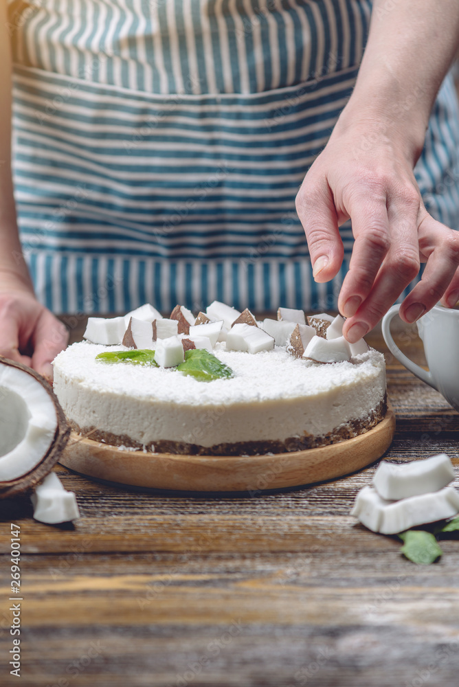 Confectioner decorates coconut raw cake with white pulp and mint. Healthy vegan dessert. Gluten and sugar free food