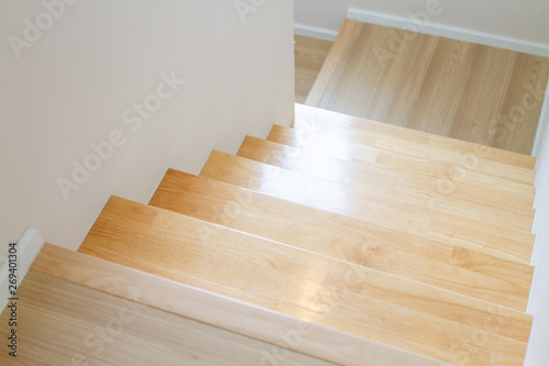The design of staircase inside the house are paved with light brown wood laminate.