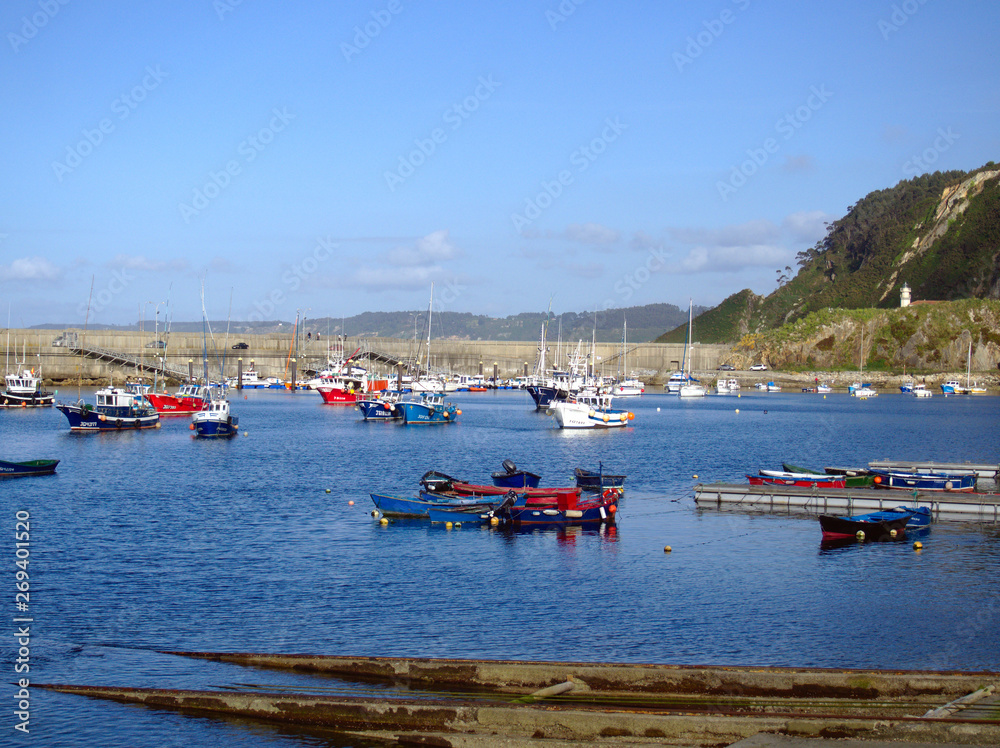 Colorful boats anchored in the port of Cudillero under the lighthouse.