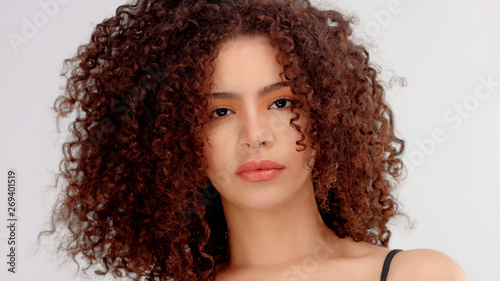 hair blowing closeup portrait of mixed race model with freckles watching to the camera. Piersing in nose