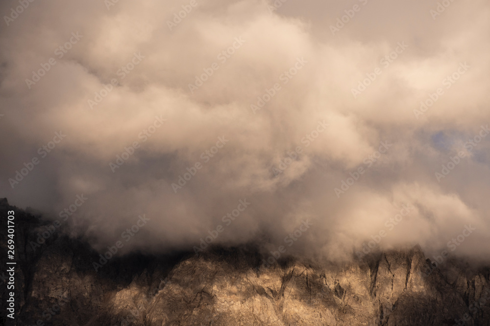 Stunning view of clouds covering mountain peak and been illuminated by sunlight Stunning view of clouds covering mountain peak and been illuminated by sunlight