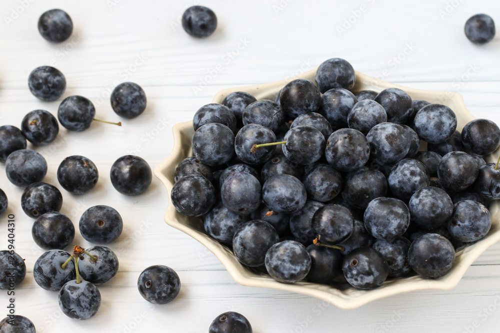 Berries blackthorn are located in a plate on a white background Berries blackthorn are located in a plate on a white background