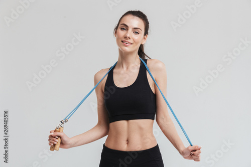Beautiful young sport fitness woman make exercises with equipment isolated over grey wall background. © Drobot Dean
