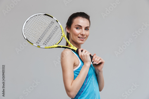 Sport fitness woman tennis player make exercises isolated over grey wall background.