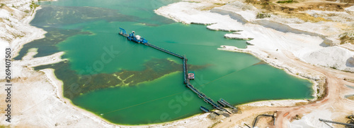 Aerial view of a blue-green quarry pond for quartz sand in Germany with the suction dredger and the conveyor belt for the sand, minng