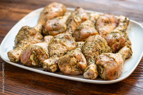 Chicken drumsticks on white dish, wooden background