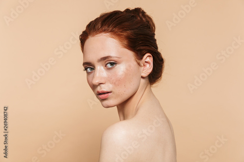Foto Young redhead woman posing isolated over beige wall background.