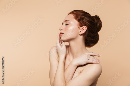 Fototapeta Amazing young redhead woman posing isolated over beige wall background