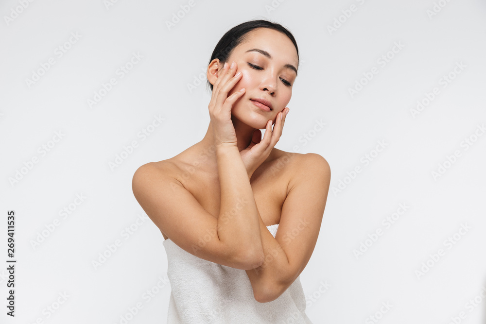 Portrait of attractive half naked asian woman touching her clear skin and looking downward Portrait of attractive half naked asian woman touching her clear skin and looking downward