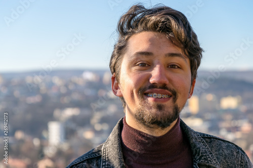 Portrait of a handsome young man with braces outdoors.  A man with braces smiling at the camera