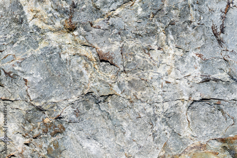 Naklejka premium Macro view of cracked stone surface brown and gray color. Detailed nature pattern texture or background taken in natural environment. Weathered over years, unique, inimitable effect to textured design