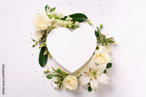 Frame of white flowers, paper heart over light background. Valentines day, Woman day concept. Spring or summer banner with copy space