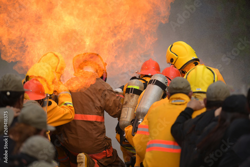 close up action of two firefighters water spray by high pressure nozzle to fire surround by smoke with flare and copy space Firemen on duty fight fire