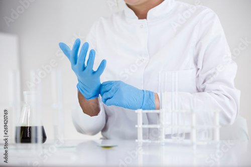 Scientist working with pharmaceutical cbd oil in a laboratory putting gloves