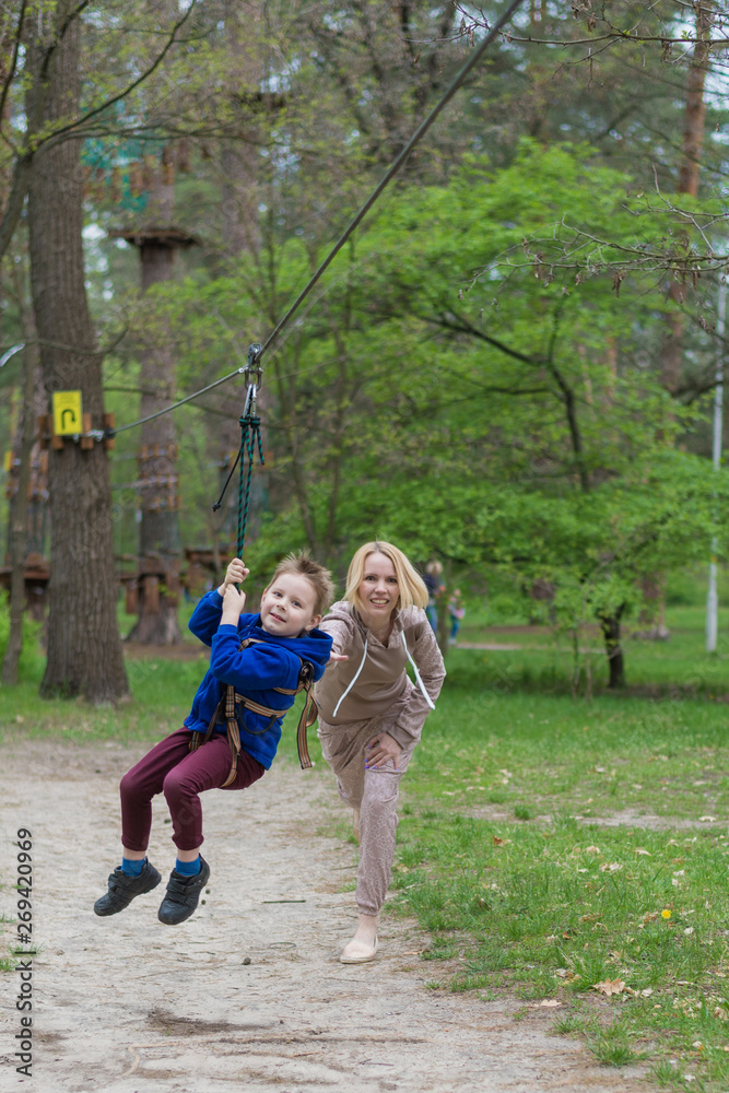 Mom rolls her son on the cable car. Leisure activities in the park. Mutual interaction between mother and child.