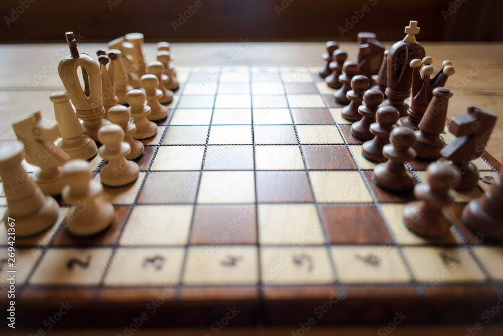 Wooden chess board with figures during the game on rustic wooden table background Wooden chess board with figures during the game on rustic wooden table background