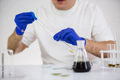 Scientist working with pharmaceutical cbd oil in a laboratory with glass equipment