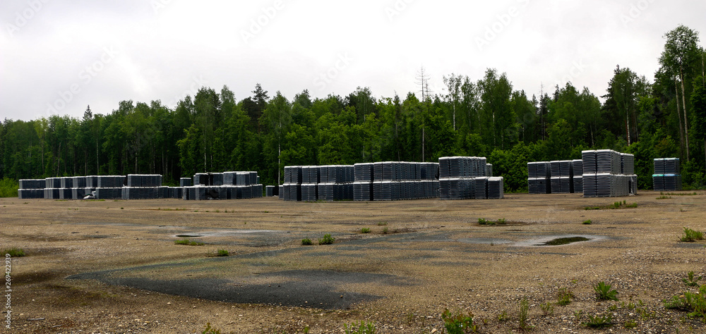 Finished products of clean bottles are packed in pallets. Racks with bottles are in abandoned area near glass factory near forest. Finished products of clean bottles are packed in pallets. Racks with bottles are in abandoned area near glass factory near forest.