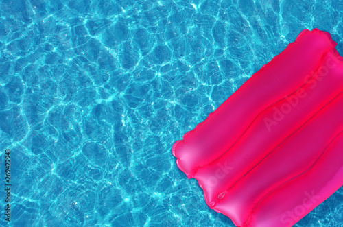 Pink inflatable pillow on the surface of the water in the pool.