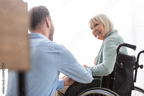 Fototapeta Naklejka Na Ścianę i Meble -  back view of man near disabled senior mother at home