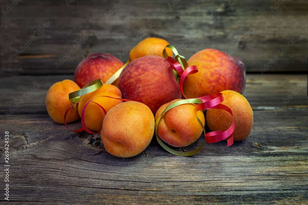 Ripe fruits of peaches and apricots close up on a wooden board Ripe fruits of peaches and apricots close up on a wooden board