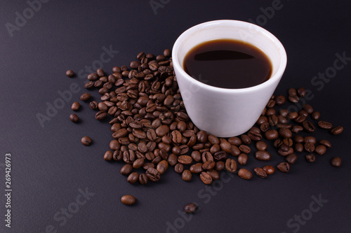 White tableware full of espresso stands in coffee beans © Aleksandr_Villou