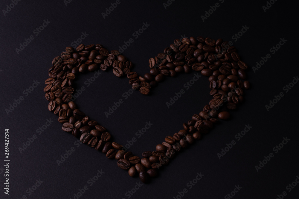 Heart lined with grains of coffee on a dark background top view