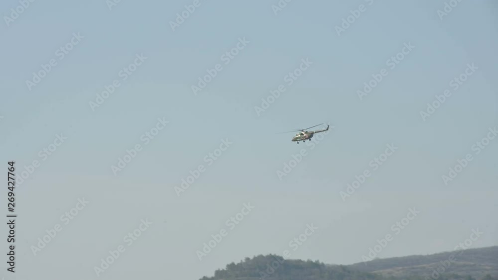 Military helicopter of the Russian air force flies in the blue clear sky against the background of the mountains of the North Caucasus Military helicopter of the Russian air force flies in the blue clear sky against the background of the mountains of the North Caucasus