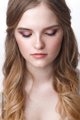 close-up of a positive young woman bride with professional wedding makeup pastel colors and hair styling curls.