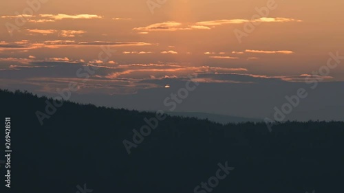 Superzoom plan timelapse sunset through sunset clouds in orange tones. Low key photo