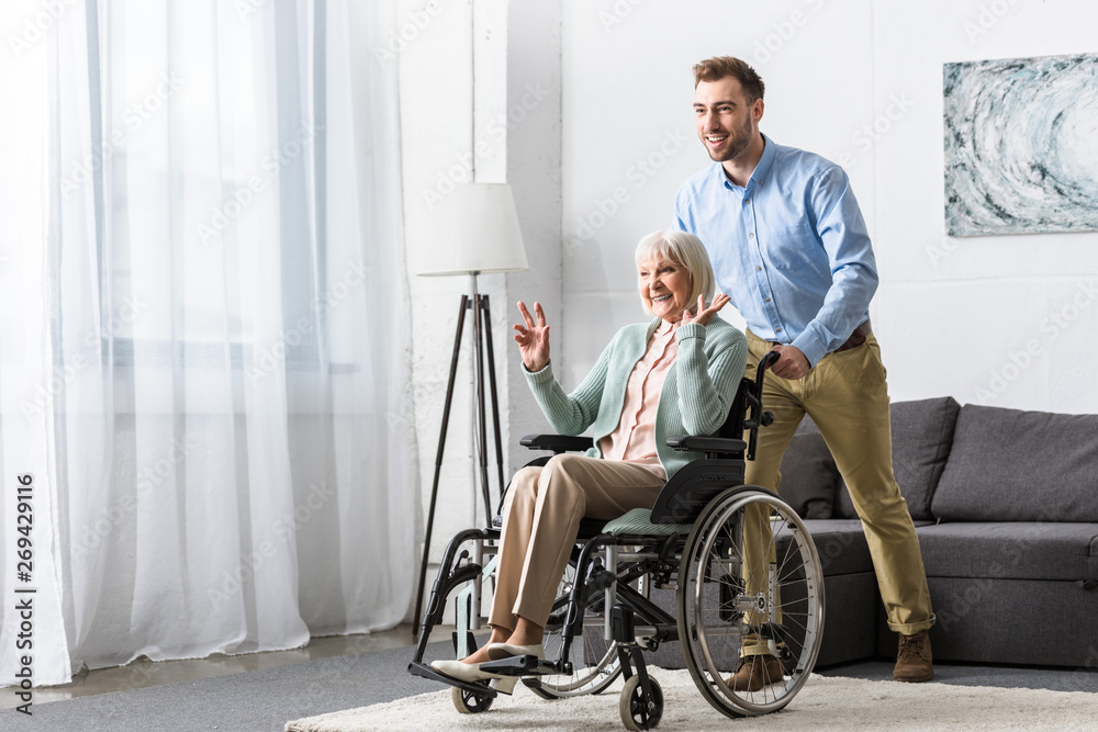 smiling man carrying disabled senior mother on wheelchair smiling man carrying disabled senior mother on wheelchair