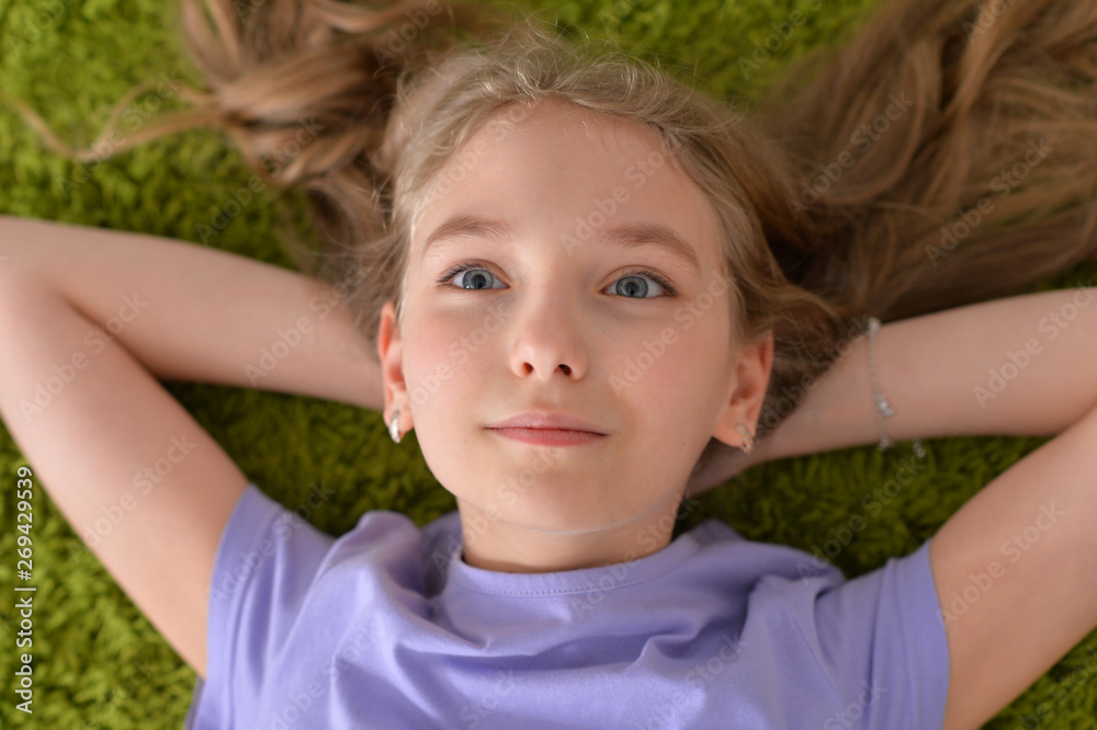 Portrait of funny smiling little girl lying on green carpet Portrait of funny smiling little girl lying on green carpet