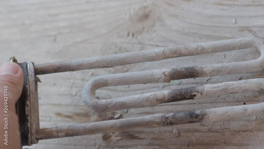Burnt-out heating element from a washing machine. Man is touching turbular electric heating element covered with limescale. Burnt-out heating element from a washing machine. Man is touching turbular electric heating element covered with limescale.
