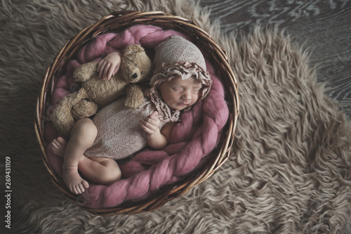 Fototapeta Naklejka Na Ścianę i Meble -  Newborn girl sleeping in basket, dark tone. Posing
