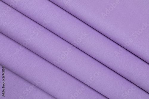 Rough cotton fabric structural with development of violet color. Large strings of a basis of material. Fabric is put by accurate geometrical folds