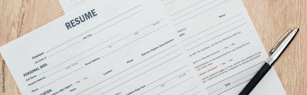 panoramic shot of print resume templates and pen on wooden table