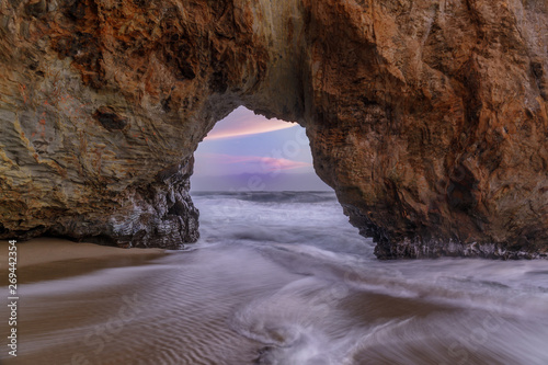 Sunset Through Sea Arch in Hole in the Wall beach. Bonny Doon, Santa Cruz County, California, USA.
