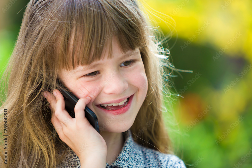 Cute child young girl talking on cellphone outdoors. Children and modern technology, communication concept. Cute child young girl talking on cellphone outdoors. Children and modern technology, communication concept.