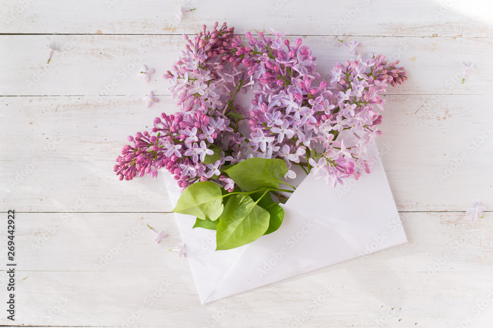 Envelope with lilac on wooden white background